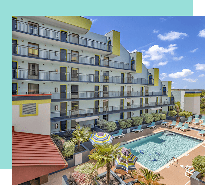 A large hotel with a pool and a sky background