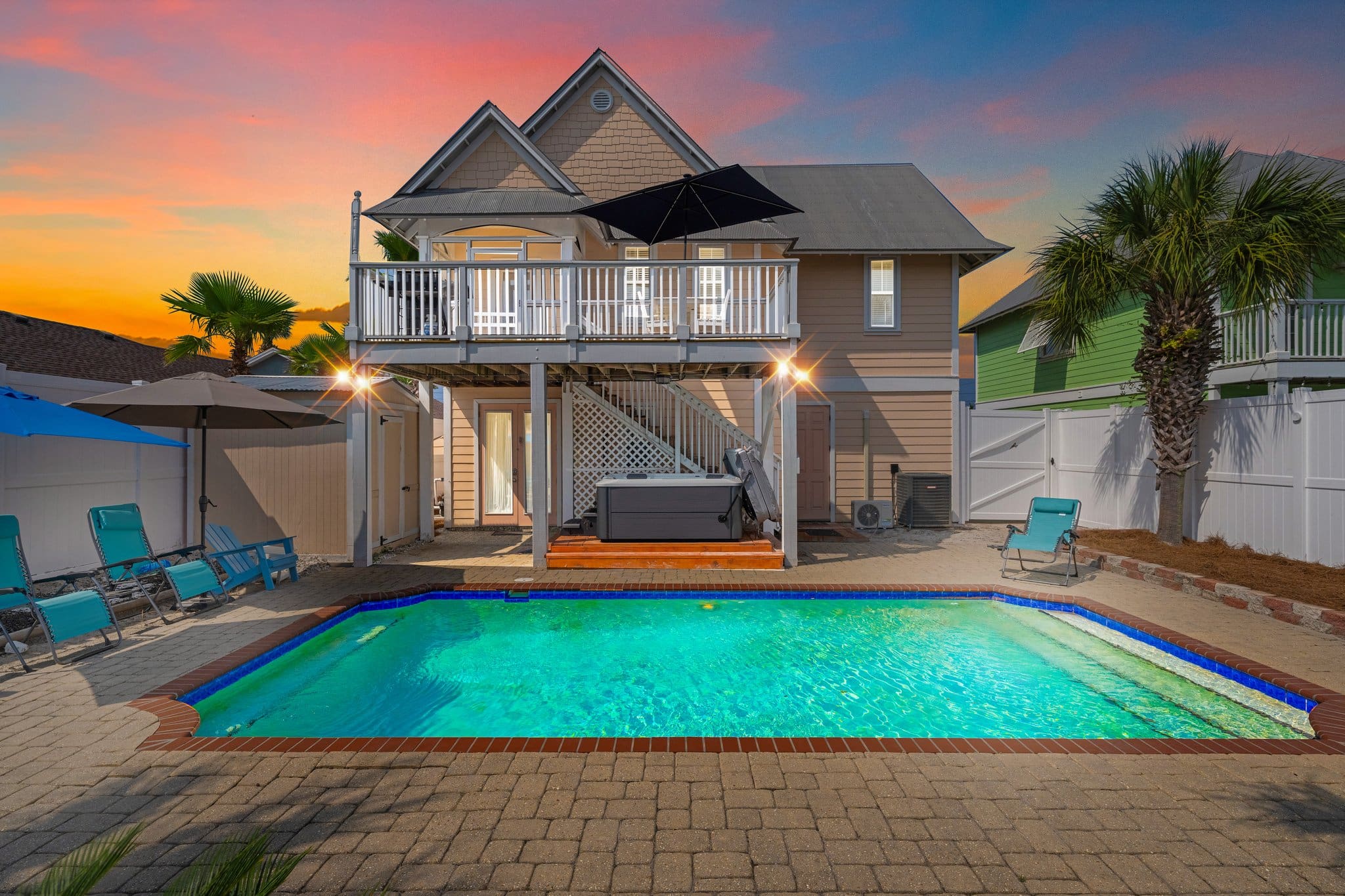 A pool and patio area with a house in the background.