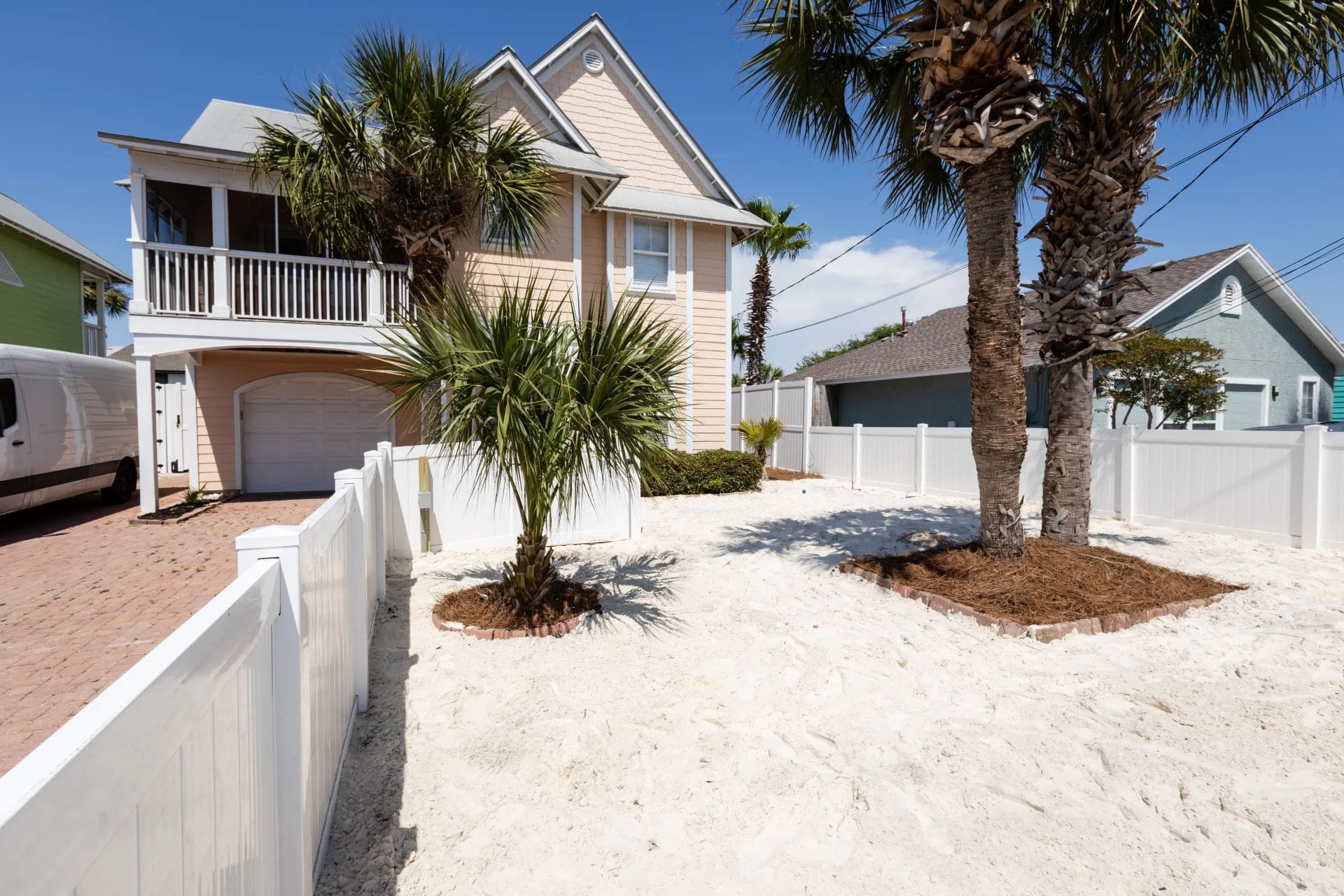 A house with palm trees and white fence in the background.