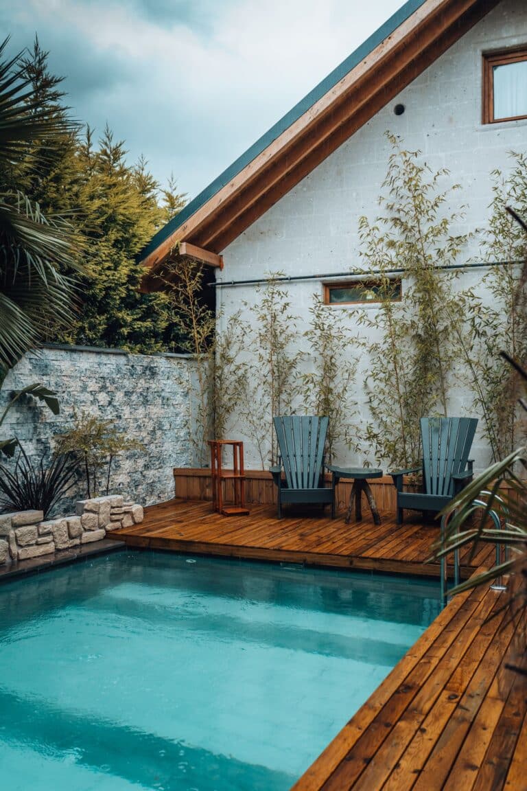 Cozy backyard pool deck with adirondack chairs and palm trees