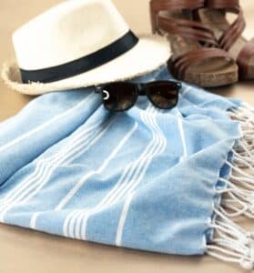 Flat lay of hat, sunglasses, sandals, and beach towel