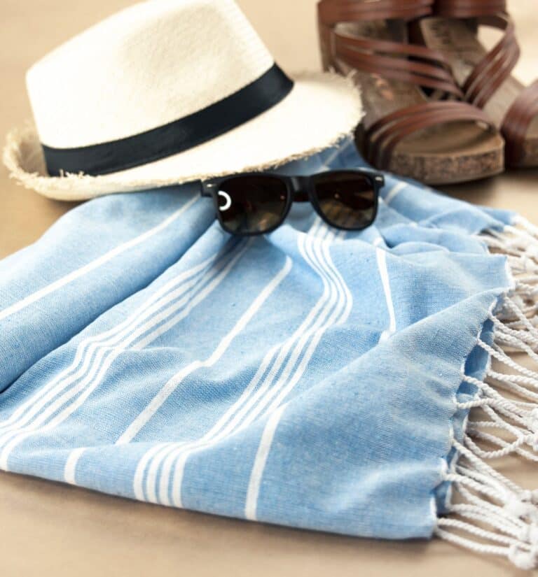 Flat lay of hat, sunglasses, sandals, and beach towel