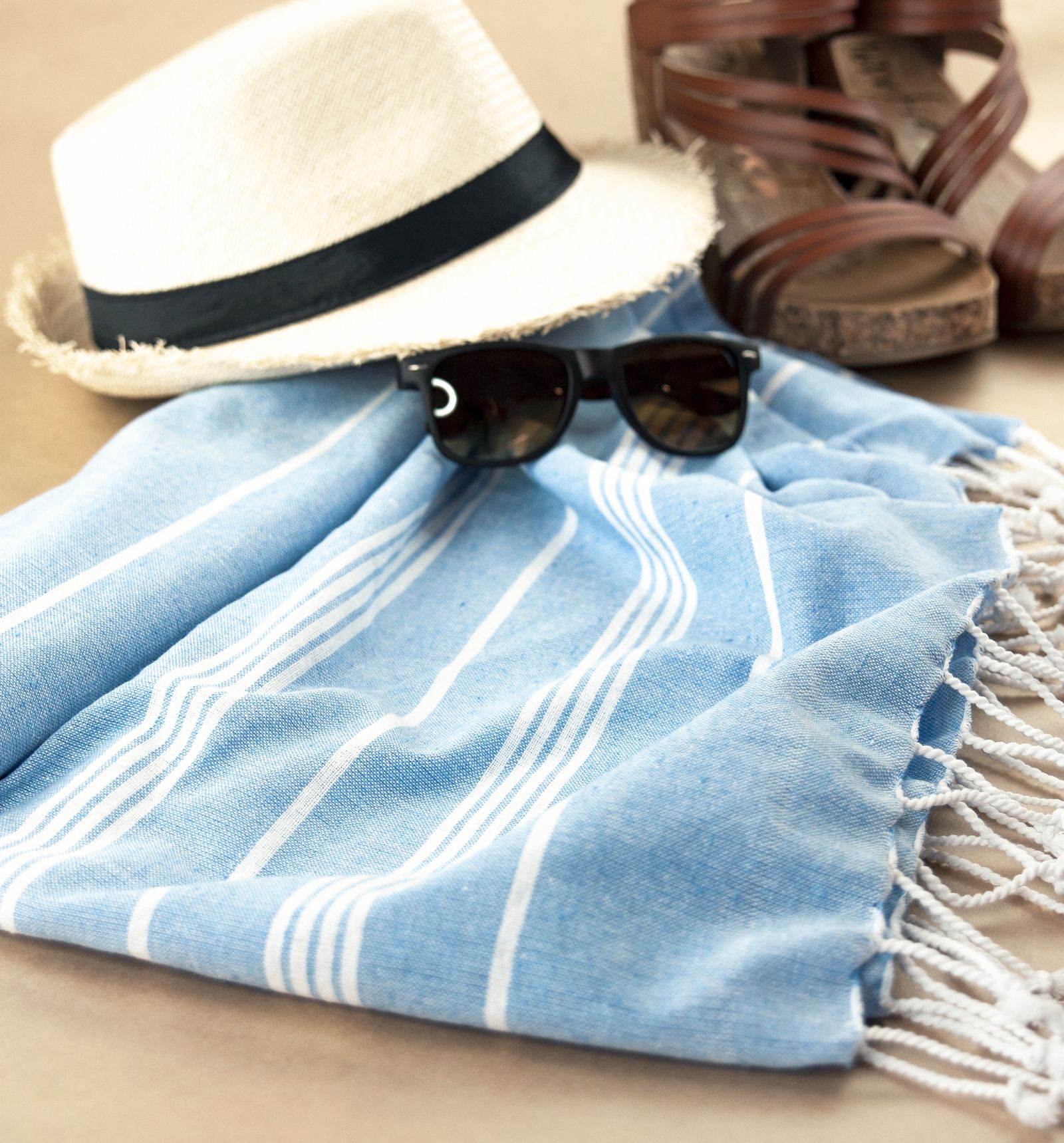 Flat lay of hat, sunglasses, sandals, and beach towel